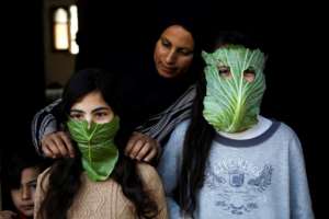 A Palestinian mother entertains her children with makeshift masks made of cabbage in Beit Lahia in the northern Gaza Strip on April 16, 2020. By MOHAMMED ABED (AFP)