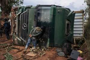 A passerby looks into a capsized truck in the middle of National Highway 27 in Ituri.  By ALEXIS HUGUET (AFP)