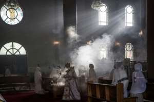 A priest wafts incense at the Bole Medhanialem Church in Addis Ababa, on June 20, 2021 during an early morning service as women congregate. By MARCO LONGARI (AFP)