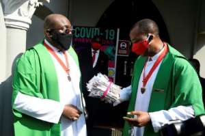 A priest holds a pack of face masks outside a church in Lagos following the reopening of churches and lifting of restrictions on religious gatherings by the Nigerian government. By PIUS UTOMI EKPEI (AFP)