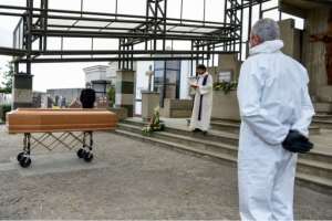 A priest reads funeral rites by a coffin in a cemetery in Grassobbio, Lombardy, Italy as pallbearers stand by. By Piero CRUCIATTI (AFP)