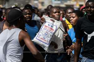 A protester holds a bag of corn meal with a price written on it. Soaring inflation and shortage of basic goods have fuelled anger. By Zinyange Auntony (AFP)