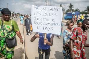 A protestor at a rally last month waved a placard stating, "Talon, let the exiled citizens come back to rebuild the country." By Yanick Folly (AFP)