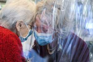 A resident at the Domenico Sartor nursing home near Venice hugs her visiting daughter through a plastic screen in a so-called