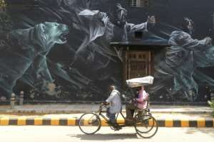 A rickshaw driver carries passengers wearing face masks in New Delhi during a government-imposed nationwide lockdown. By SAJJAD HUSSAIN (AFP)