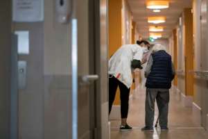 A staff member at a retirement home in Thises helps a resident on the 31st day of a strict lockdown in France. By SEBASTIEN BOZON (AFP)