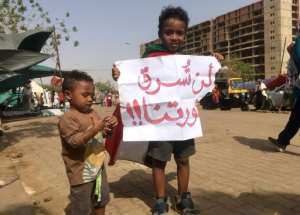 A Sudanese boy holds a sign reading in Arabic 