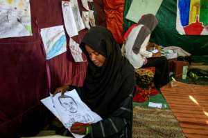 A Sudanese girl draws a portrait of Ahmad al-Kheir, a teacher who died from wounds suffered in detention during Bashir's regime, outside the army headquarters in the capital Khartoum. By Ebrahim Hamid (AFP)