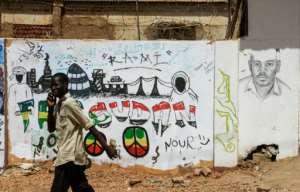 A Sudanese protester walks past a recently painted mural of Ahmad al-Kheir, a teacher who died from wounds suffered in detention during Bashir's regime, outside the army headquarters in the capital Khartoum. By Ebrahim Hamid (AFP)