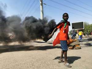 A Sudanese youth draped in the national flag stands by burning tyres during a protest in Khartoum on October 26, 2021, to denounce the military coup that overthrew the transition to civilian rule. By - (AFP)