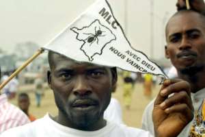 A supporter of newly appointed DR Congo vice-president Jean-Pierre Bemba holds a flag of the Congolese Liberation movement (MLC), reading 'with god we shall overcome', outside the People's Palace in Kinshasa, in 2003