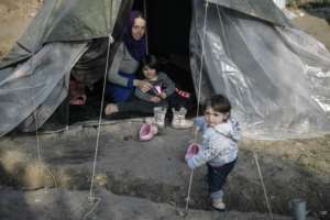 A Syrian woman sits in her tent with her children in the Vial refugee camp, on the Greek island of Chios, which is overcrowded with 5,000 people. By LOUISA GOULIAMAKI (AFP)