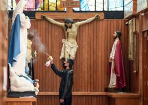 A sacristan wearing a face mask disinfects the religious statues inside the Sagrada Familia Church in Mexico City. By ALFREDO ESTRELLA (AFP)