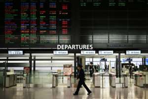 A security guard walks past a signboard showing cancelled flights at the international departures area of Narita International Airport in Narita, Japan -- Prime Minister Shinzo Abe said the country's hospitals face a