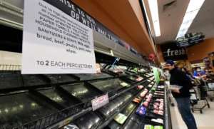 A sign announces a two-item limit for certain items as people shop for food in Monterey Park, California. By Frederic J. BROWN (AFP)