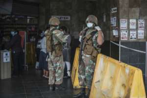 A South African National soldier stands at the entrance a supermarket in Soweto. By MARCO LONGARI (AFP)