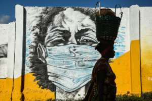 A Tanzanian woman walks in front of a mural painted by the Wachata artists group to raise awareness about avoiding the spread of coronavirus. Magufuli has claimed prayer saved the country from Covid-19. By Ericky BONIPHACE (AFP/File)