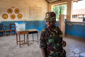 A Tanzanian security officer waits to cast her ballot in early voting. By Patrick Meinhardt (AFP)