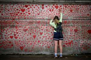 A woman draws on the National Covid Memorial Wall in London. By Tolga Akmen (AFP)