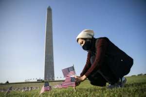 A woman places a flag at a memorial on the National Mall in Washington fo the more than 200,000 people in the United States who have died of Covid-19. By Alex Edelman (AFP)
