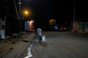 A woman walks home through empty streets after the 7:00 pm curfew having closed her stall late in Kibera. By Kabir Dhanji (AFP)