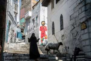 A woman walks past a mural of Egyptian footballer Mohamed Salah in Cairo on June 17, 2019, four days ahead of the African Cup of Nations debut (CAN). By Khaled DESOUKI (AFP)