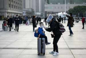 A woman wearing a face mask adjusts her child's mask as they arrive at Wuhan's Hankou rail station to take one of the first trains to leave the Chinese city since a ban on outbound travel was lifted. By NOEL CELIS (AFP)