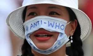 A woman wearing a mask to protest the WHO, which warned that a vaccine is not enough to stop the virus -- the population must want to take it. By Ina FASSBENDER (AFP)