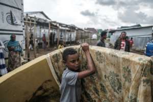 A young boy takes a mattress handed out by an aid group at the Azezo camp. By EDUARDO SOTERAS (AFP)