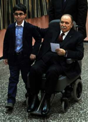 Abdelaziz Bouteflika is pushed into a wheelchair next to his nephew before voting in a polling station in Algiers while he ran for reelection on April 17, 2014. By FAROUK BATICHE (AFP / File)