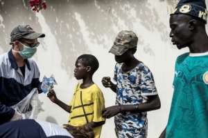 Aid: A worker from Village Pilote hands out water and sandwiches to street children. By JOHN WESSELS (AFP)