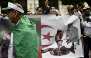 Algerian protesters parade a national flag showing the country still in the grip of key allies of Abdelaziz Bouteflika after the ailing president quit on Tuesday. By Ryad KRAMDI (AFP)