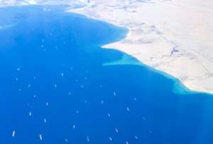 An aerial view taken from the porthole of a commercial plane shows ships stranded in the Red sea, as the MV 'Ever Given' (Evergreen) container ship continues to block the Suez Canal in both directions. By Mahmoud KHALED (AFP)