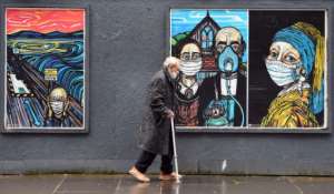 An elderly man wearing a face mask walks past graffiti depicting the subjects of famous artworks wearing masks in Glasgow, Scotland. By Andy Buchanan (AFP)