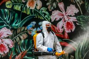 An employee wearing protective gear disinfects a shopping mall as a preventive measure against COVID-19 in Caxias do Sul, Brazil. By SILVIO AVILA (AFP)