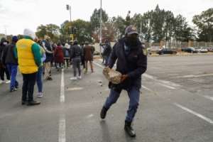 Anger: A policeman removes a rock from the road as Soweto residents picket state electricity supplier Eskom over disruptive power cuts. The protest was in June, at the height of the South African winter. By Phill Magakoe (AFP)