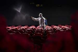 Astaff member sprays disinfectant at a cinema as it prepares to reopen to the public in Shenyang, China. By STR (AFP)