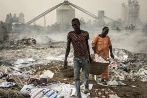 Artisanal workers carry a basket filled paper and wood shavings for smoking fish on the shorefront at Bagny. Their product is sold around West Africa, but the hidden environmental cost is high. By JOHN WESSELS (AFP)