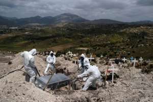 Cemetery workers wearing protective gear bury an unclaimed COVID-19 victim in Tijuana, Baja California state, Mexico. By Guillermo Arias (AFP)