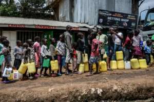 Children wait in line for water, distributed for free in the Nairobi slum of Kibera last week. Health experts say close queueing breaks the rule of social distancing to prevent virus infection. By Gordwin ODHIAMBO (AFP)