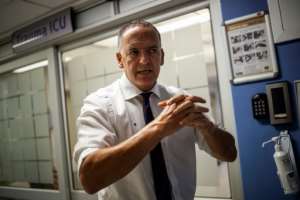 Doctor and Netcare Group Chief Executive Officer (CEO) Richard Friedland (R) explains how to wash hands. By Michele Spatari (AFP/File)