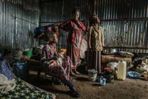 Eritrean refugee Seble Melkamu (left) cuddles her son as she talks with other refugees in her shelter at a camp in the town of Azezo. By EDUARDO SOTERAS (AFP)