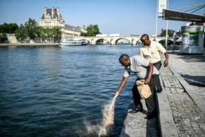 Eric and Bernard pour soil from Bisesero land into the Seine river in Paris. By STEPHANE DE SAKUTIN (AFP)