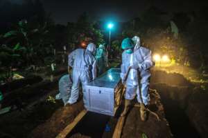 Gravediggers bury a Covid-19 coronavirus victim at a cemetery in Bogor, on the outskirts of Jakarta, Indonesia on March 2, 2021. By ADITYA AJI (AFP)