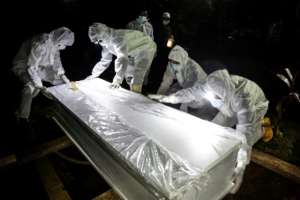 Graveyard workers in full prtective gear move a coffin in Bogor, Indonesia. By ADITYA AJI (AFP)