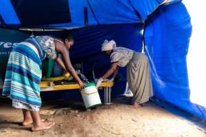 Gwena collects water in a bucket as she prepares for a long day. By Jekesai NJIKIZANA (AFP)