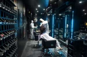 Hairdressers in protective suits attend to customers at a hair and beauty salon in Ahmedabad, India. By SAM PANTHAKY (AFP)