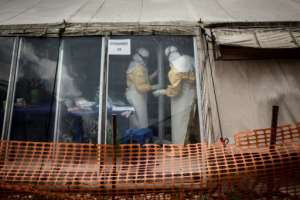 Health workers are observed inside the "red zone" of an Ebola treatment center that was attacked in March. By JOHN WESSELS (AFP / File)