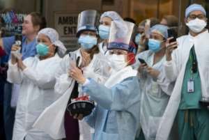 Health workers react to people applauding in front of Mount Sinai Hospital in Queens, New York to show gratitude to medical staff and essential workers on the front lines of the coronavirus pandemic. By Johannes EISELE (AFP)
