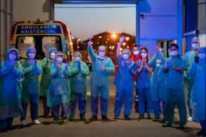 Healthcare workers dealing with the new coronavirus crisis applaud in return as they are cheered on by people outside a hospital in Burgos, Spain. By CESAR MANSO (AFP)